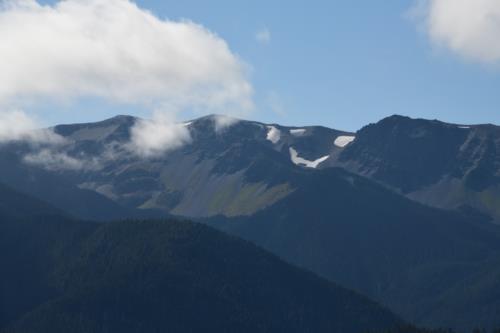 White clouds, blue sky on top of a snow clad mountain